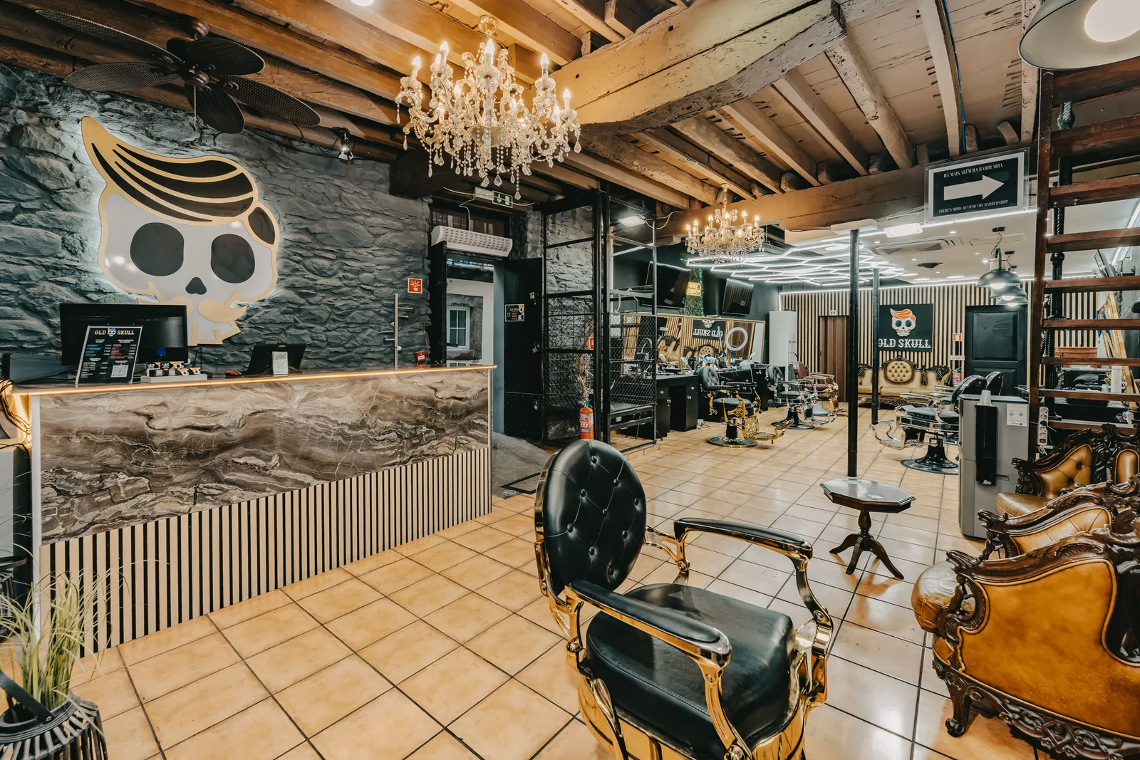 Zona de receção da Old Skull Rua dos Aranhas com lustres e cadeiras de barbeiro