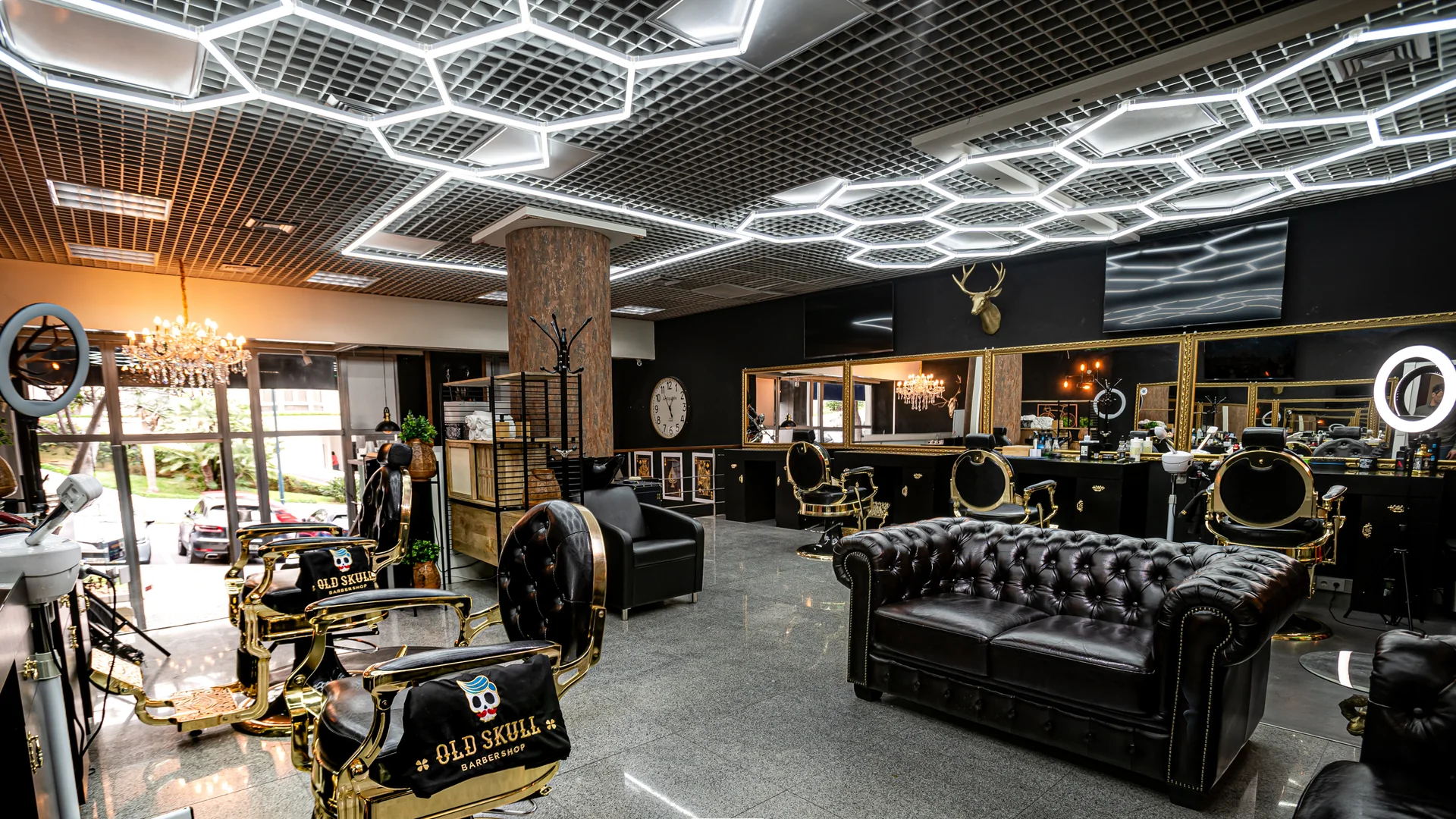 Interior da Old Skull BarberShop junto ao Fórum Madeira, com cadeiras clássicas, espelhos dourados e iluminação geométrica